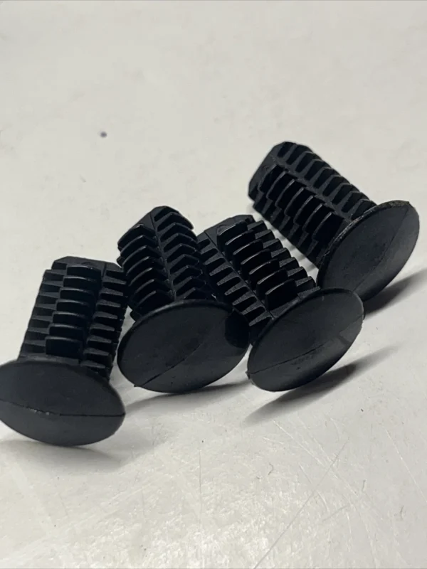 10040 | Harley-davidson® Online Close-up of several small black plastic gears with external teeth and flat circular bases resting on a light surface, arranged in a row.