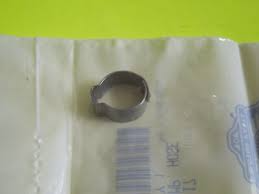 Small metal hose clamp ring resting on a crumpled paper bag with blue text and barcode nearby.