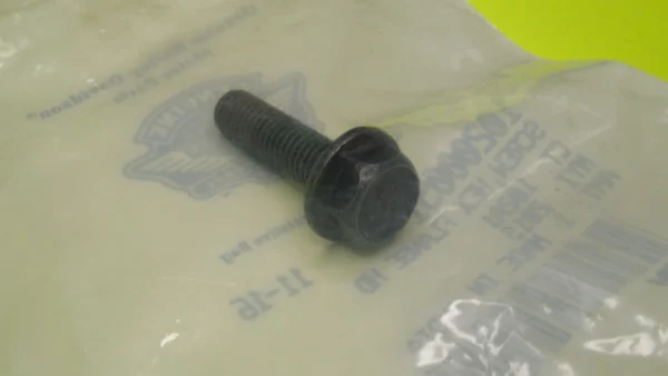 Black hex bolt with threaded shaft resting on a pale plastic bag.