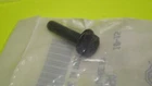 Small black plastic knob-like object resting on a clear plastic bag on a bright lime-green surface.