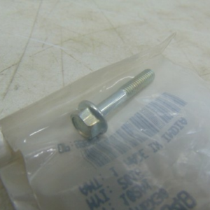 Hex bolt with a accompanying nut lying on clear plastic packaging on a scratched workbench surface.