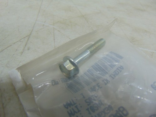 10200348 | Harley-davidson® Online Hex bolt with a accompanying nut lying on clear plastic packaging on a scratched workbench surface.