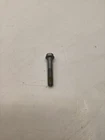Small metal screw lying on a light gray textured surface.