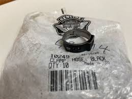 Close-up of a metal hose clamp on a plastic-wrapped package with a label reading 'HOSE: BLACK' and a barcode.