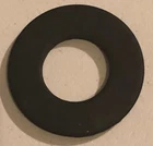 Black rubber O-ring (flat circular gasket) mounted on a light wall surface.