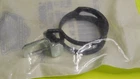 Small resealable plastic bag on a bright yellow surface containing a black circular object, possibly a strap or ring.