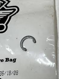 Small, open metal ring (C-shaped) resting on a plastic bag with partial text visible in the corner.