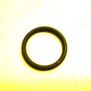Close-up of a black rubber O-ring placed on a pale yellow surface.