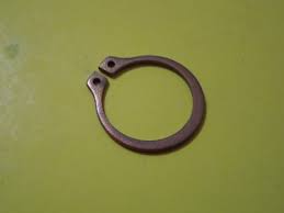 Circular metal clamp with two tab ends and holes on a green surface.