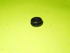 Small black rubber cap on a bright lime-yellow surface, resting flatly.