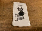 Small black coffee cup resting on a white paper bag with a barcode on a wooden table.