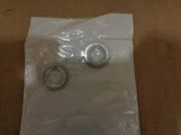 Two small metal rings on a clear plastic bag placed on a wooden surface.