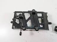 Metal bracket with levers and bolts, likely part of an automotive pedal linkage assembly.