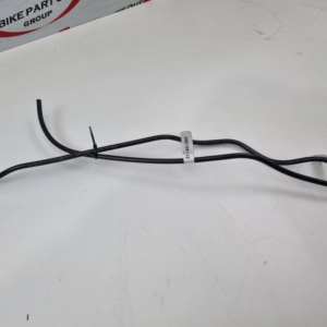 Black automotive wiring harness with a looped end, laid on a white surface with a label attached.