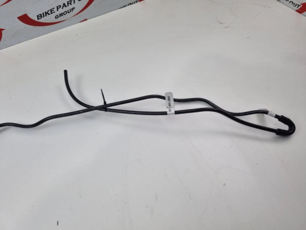 Black automotive wiring harness with a looped end, laid on a white surface with a label attached.
