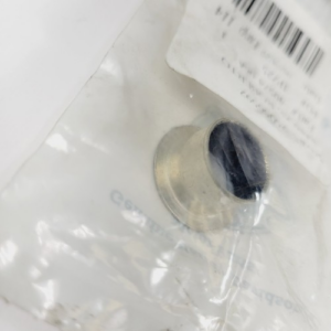 Close-up of a metallic eyelet inside a clear plastic bag, with a barcode label visible in the corner.