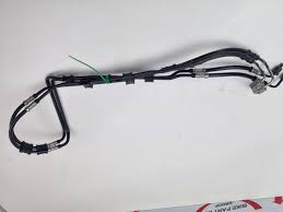 Automotive wiring harness with multiple connectors and black protective tubing laid on a white surface.