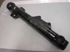 Long black automotive shock absorber with mounting brackets on a white surface.