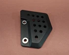 Black perforated metal plate with a grid of small holes and two larger silver-rimmed holes on a brown surface.