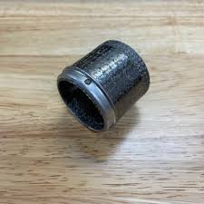 Dark metal cylindrical bushing with a hollow center on a wooden surface.