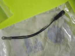Black flexible electrical cable with a metal ring terminal on one end and a small rectangular connector on the other, in a clear plastic bag.