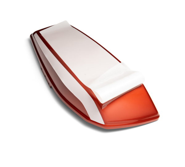 Red and white paper cutter/trimmer on a white background, handheld with a sliding blade in a desk setup.