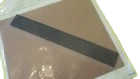 Gray rectangular strip laid diagonally across a light brown surface.