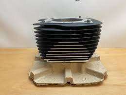 Small air-cooled engine cylinder model with stacked cooling fins on a beige display stand.