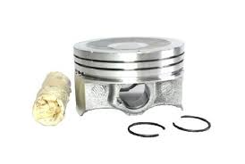 Metal engine piston with three piston rings and a wrist pin, shown with additional rings nearby (components of an engine piston assembly).