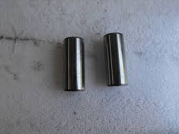 Two small shiny metal cylinders placed side by side on a light gray surface.
