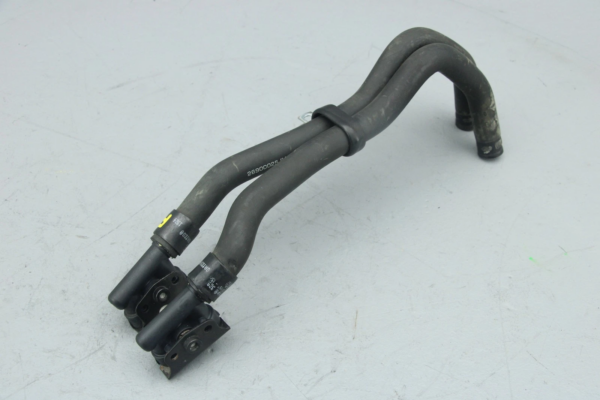 Black rubber automotive hose assembly with metal clamps and a U-shaped bend, placed on a light surface.