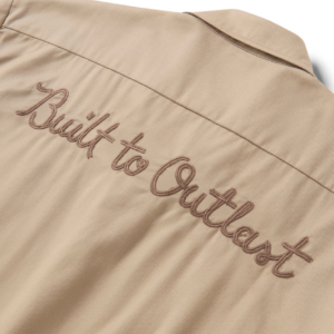 Beige jacket back with brown embroidered slogan 'Built to withstand' along the seam.