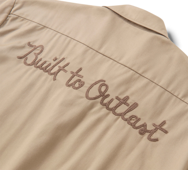 Beige jacket back with brown embroidered slogan 'Built to withstand' along the seam.
