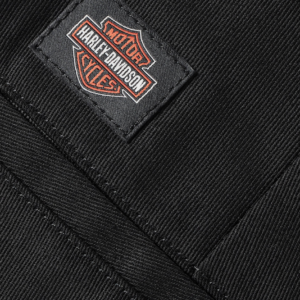 Close-up of black denim fabric with a Harley-Davidson patch sewn onto the pocket edge.