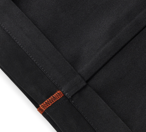 Close-up of black denim fabric with orange topstitching along a seam, highlighting reinforced stitching.
