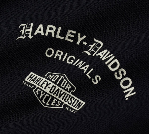Close-up of black denim with white Harley-Davidson Originals logo and shield badge reading 'Motor Harley-Davidson Cycles'