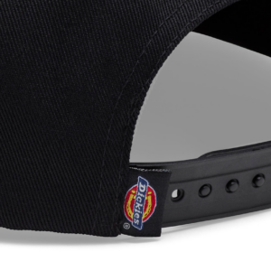 Close-up of the back of a black baseball cap showing a Dickies logo tag and adjustable plastic strap with holes.