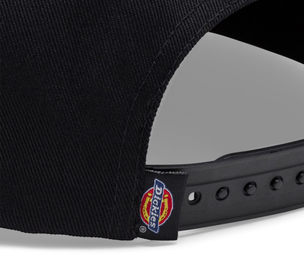 Close-up of the back of a black baseball cap showing a Dickies logo tag and adjustable plastic strap with holes.