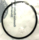 Black rubber O-ring resting on a white surface with faint printed text around its edge.